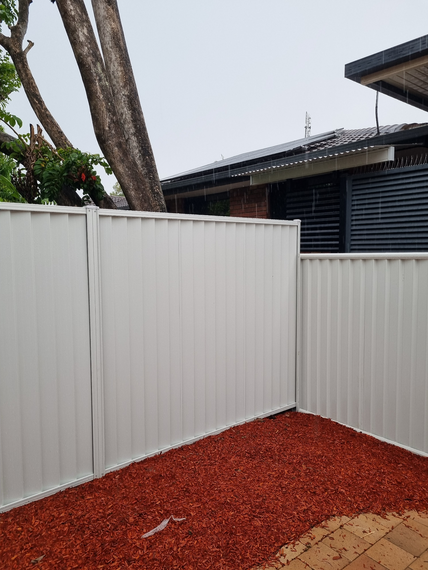 Cream Colorbond fence corner with a clean step where panels meet at the boundary.