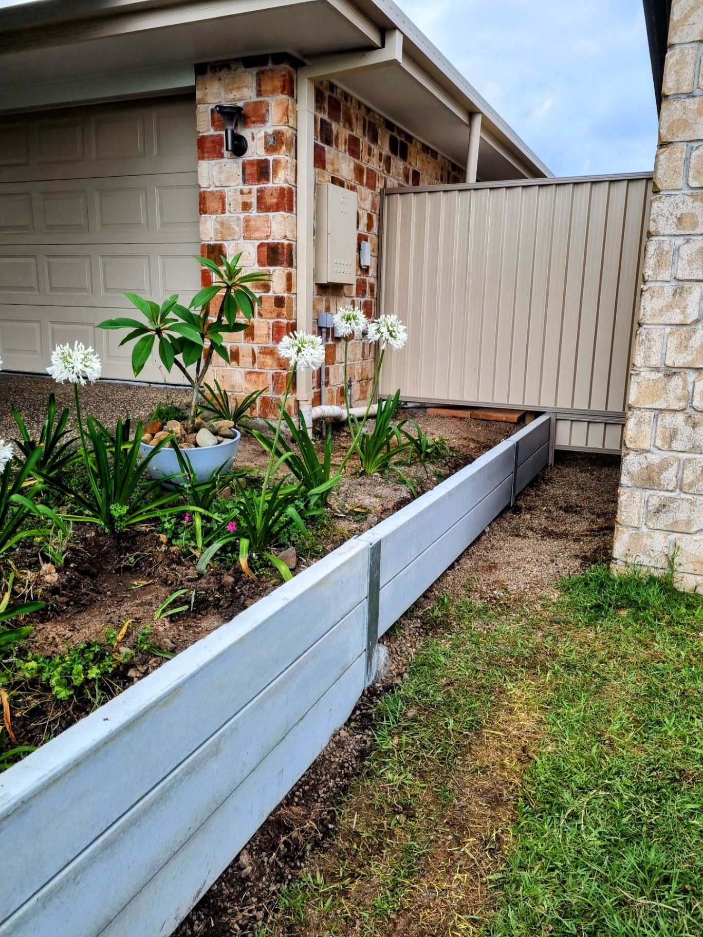 Dark Colorbond fence with hardwood sleeper plinths supporting the base — Ridgeback Fences install.